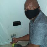 Eddie Kyles cleaing dryer vent with CoronaVirus facemask